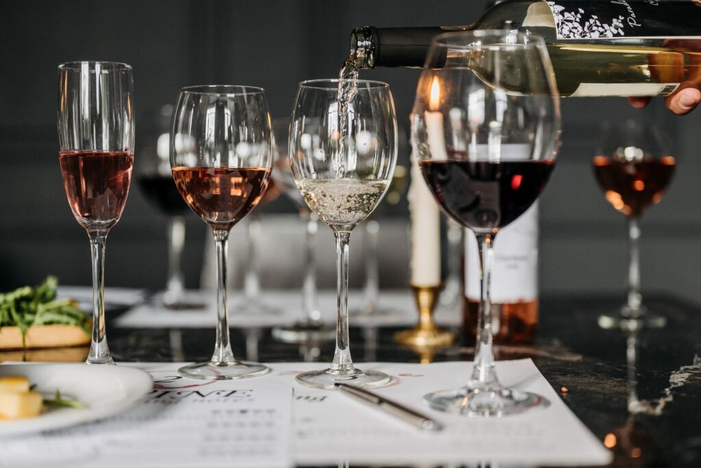 Fila de copas de vino con distintos colores (rosado, blanco y tinto) durante una cata, bien iluminadas para apreciar su color