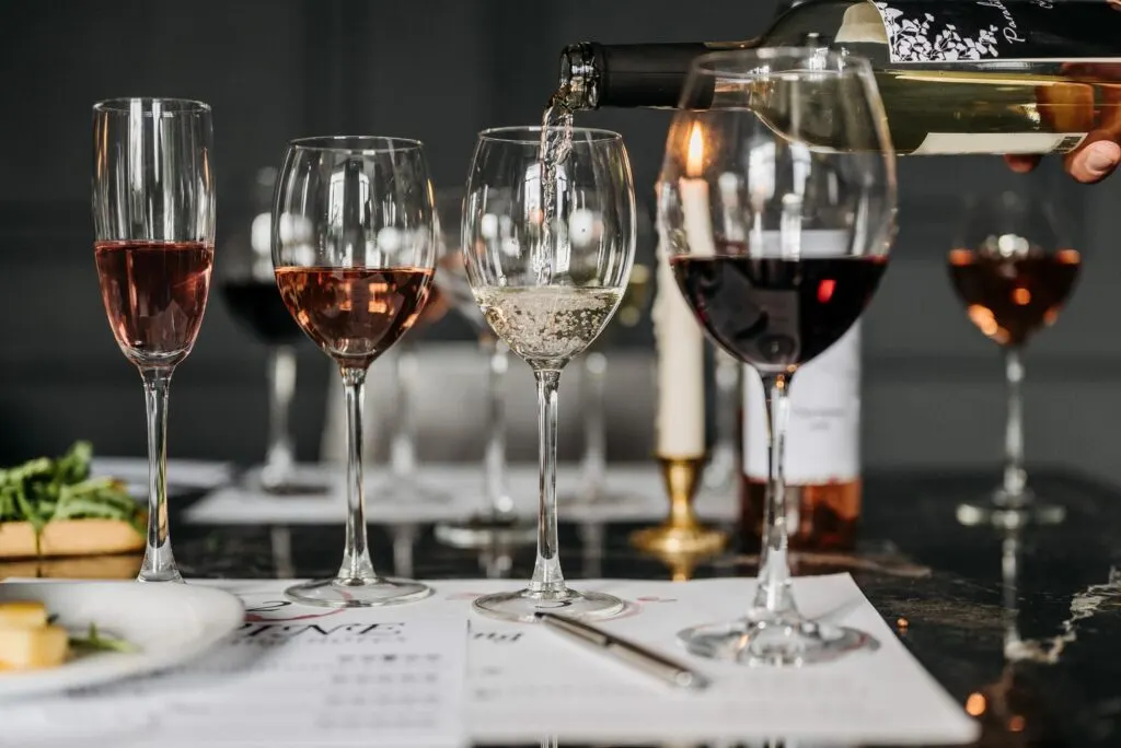 Fila de copas de vino con distintos colores (rosado, blanco y tinto) durante una cata, bien iluminadas para apreciar su color